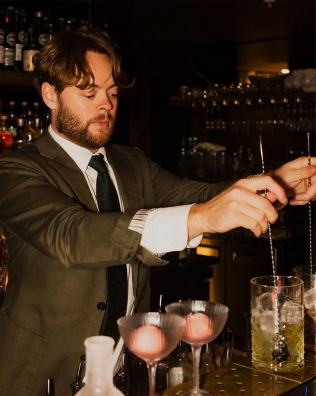 Stirring two drinks behind the bar